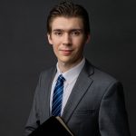 a headshot of a young man in a suit