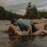 a man and woman kissing while laying on top of one another in a river