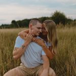 a portrait of a couple with their arms over one another in a field