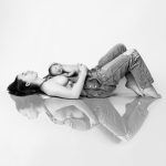 a woman laying on her back with her newborn on her stomach