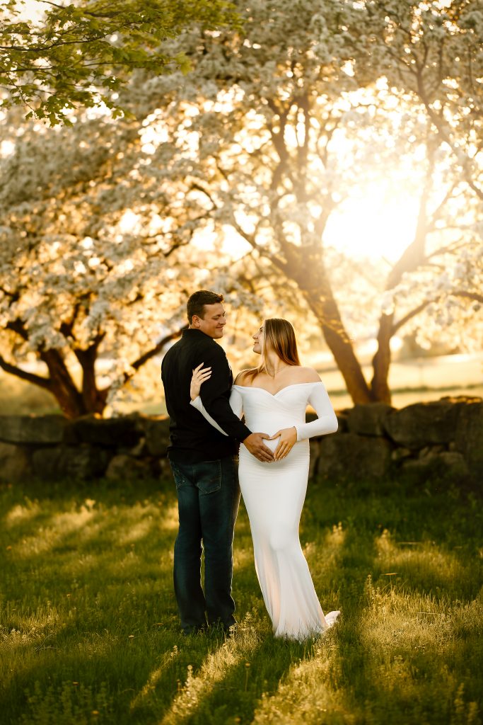 maternity photography white flowers white dress long sleeve sunset golden hour gilford new hampshire green grass husband and wife