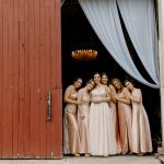wedding photography bishop farm weddings and events new hampshire wedding venue red barn bridesmaids and bride standing in doorway white curtain chandelier