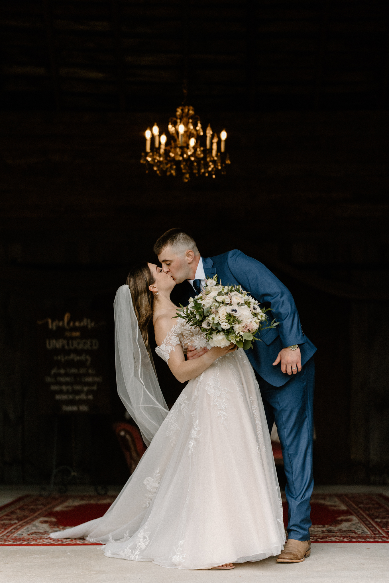 wedding photography bishop farm weddings and events new hampshire wedding venue red barn white curtain chandelier bride and groom kissing