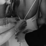 wedding photography bride getting dress zipped by mom and bridesmaid black and white alvirne memorial chapel derry new hampshire
