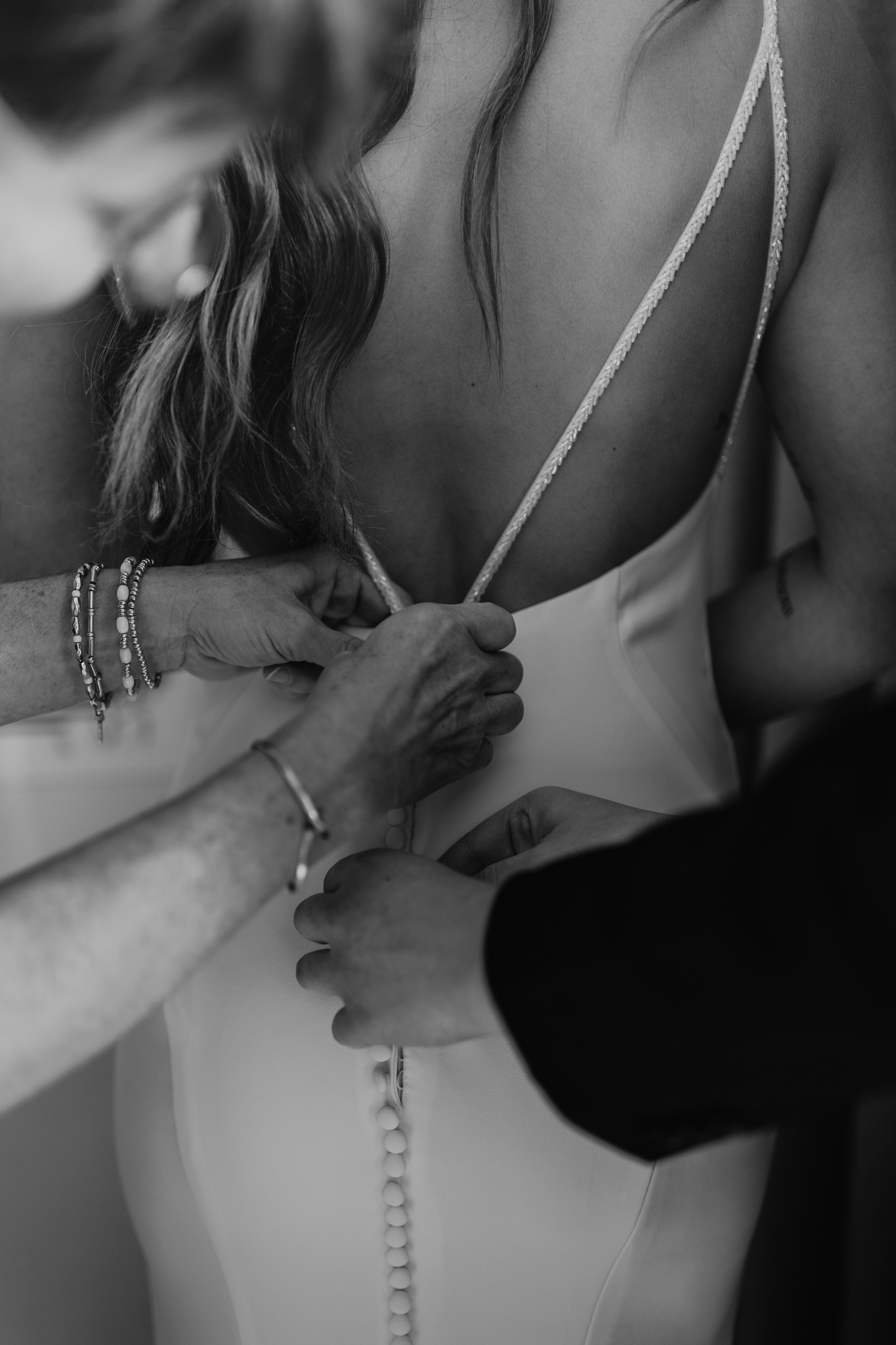 wedding photography bride getting dress zipped by mom and bridesmaid black and white alvirne memorial chapel derry new hampshire