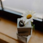 wedding photography wedding rings sitting on ring box with daisy on windowsill pikes peek new hampshire