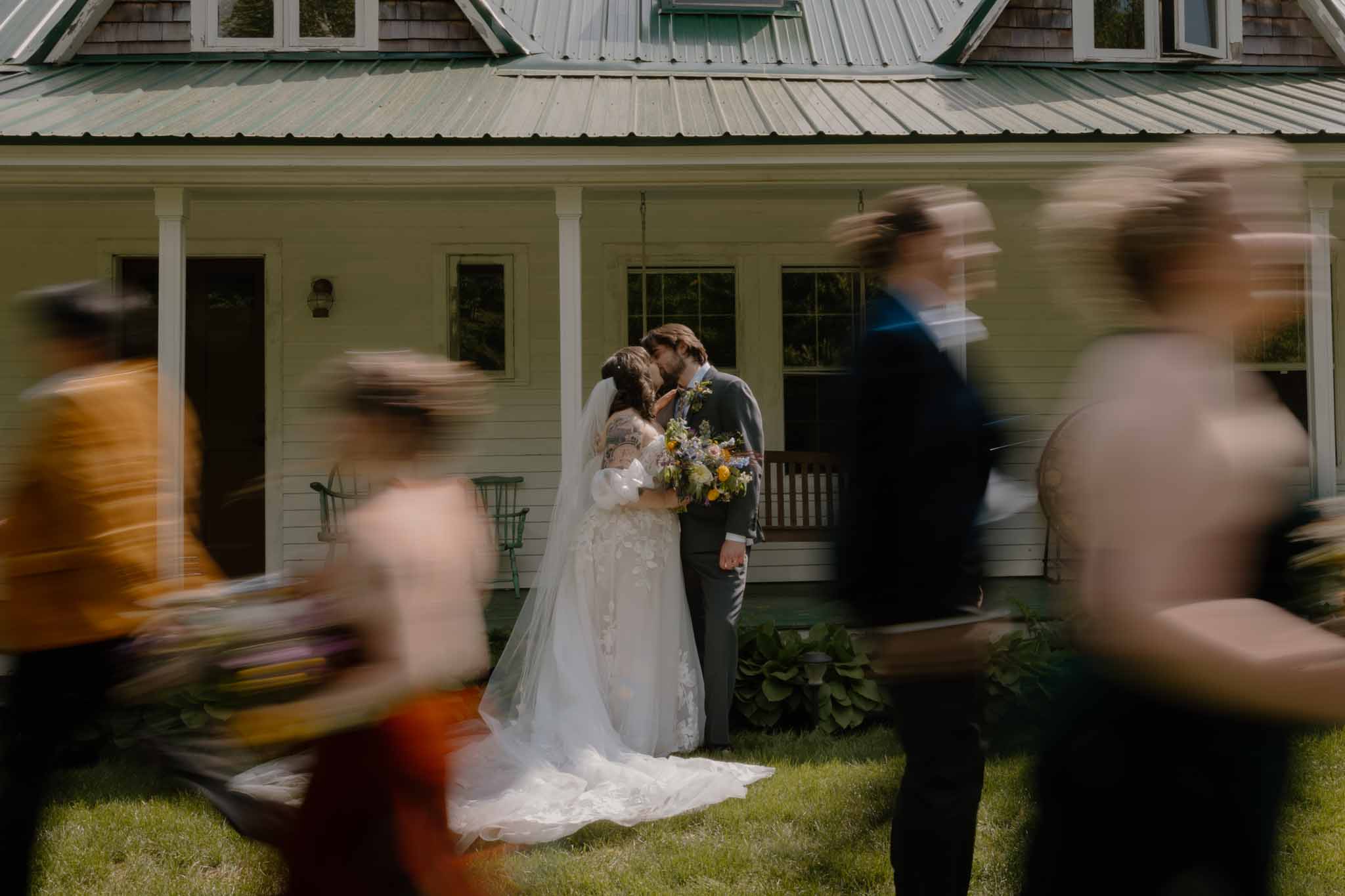 wedding photography white house bride and groom kissing bridal party walking in a blur past them locke falls farm new hampshire