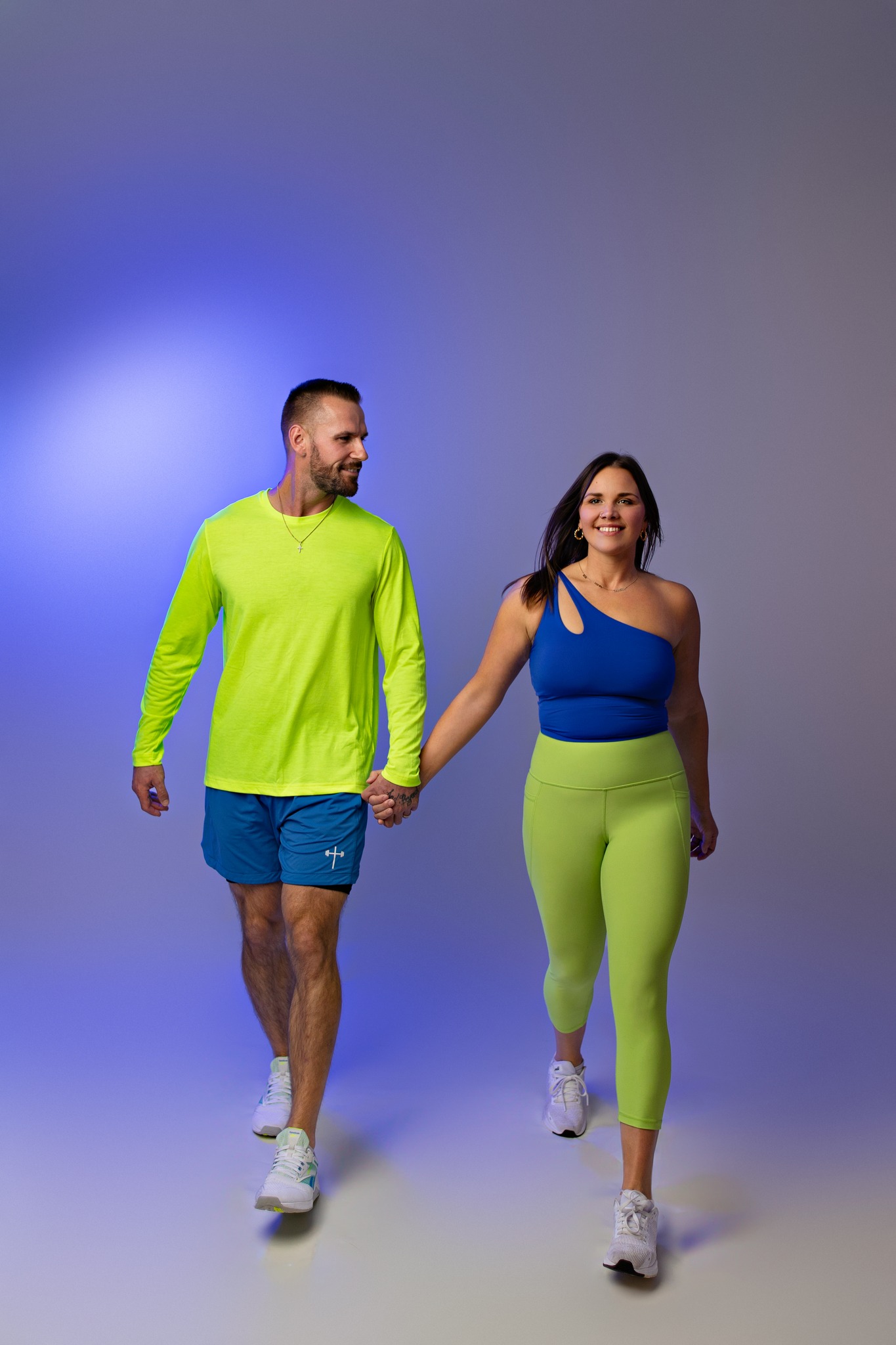 workout fitness photography husband and wife holding hands branding portraits green and blue outfits holding hands walking concord new hampshire studio
