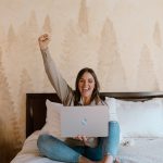 branding photography laptop woman on bed fist in air celebrating branding photography concord new hampshire