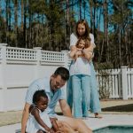 black and white family portrait holding hands pool concord new hampshire jeans white tops mom dad sisters hugging poolside