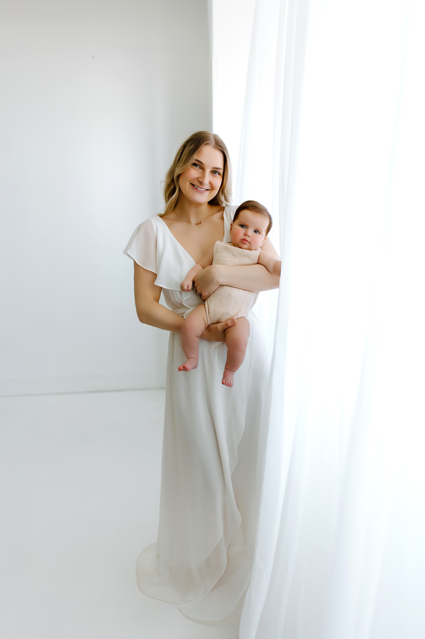 family portrait photography mom holding baby white dress white backdrop curtains concord new hampshire studio lifestyle