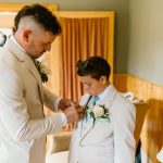 wedding photography groom pinning boutonniere on ring bearer. tan suits coleman state park wedding venue new hampshire