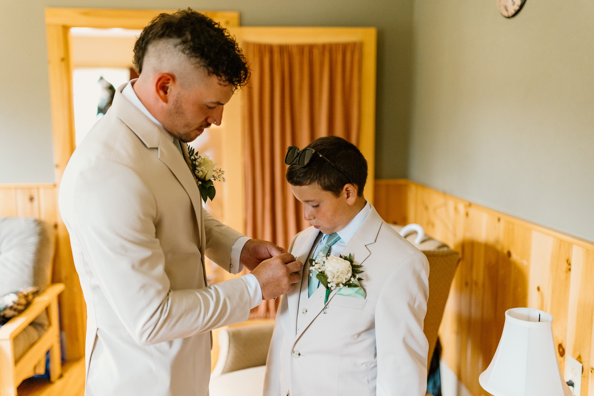 wedding photography groom pinning boutonniere on ring bearer. tan suits coleman state park wedding venue new hampshire