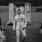 black and white wedding portrait where groom is walking down the isle smiling, nh