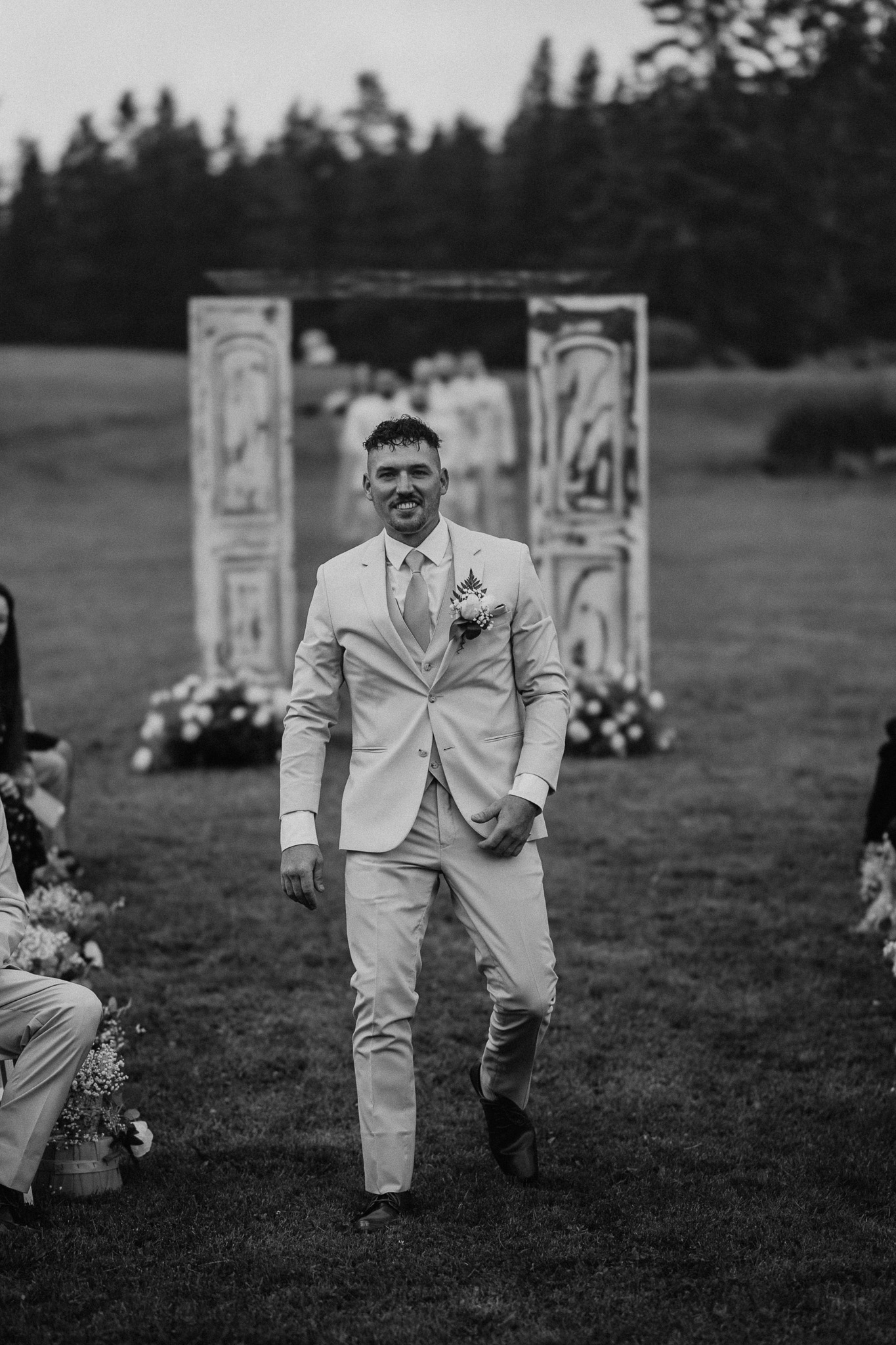 black and white wedding portrait where groom is walking down the isle smiling, nh
