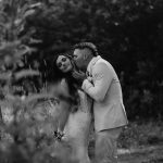 black and white wedding portrait where groom is kissing bride, woods, trees, nh