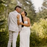 wedding portrait where bride and groom are holding each other, tan suit, outdoors, woods, nh