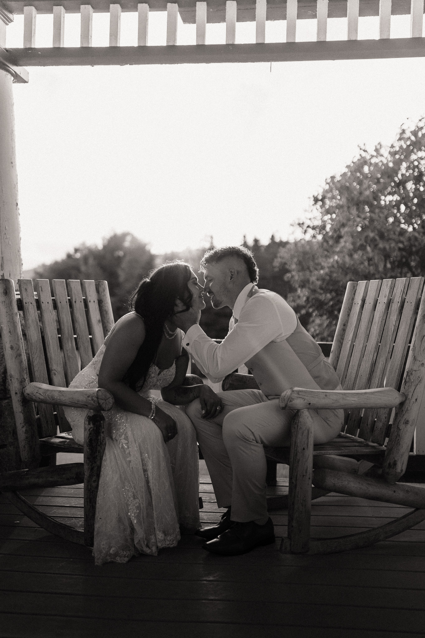 wedding portrait where husband and wife bride and groom are sitting on railing of porch, sunset, golden hour, nh sitting in chairs