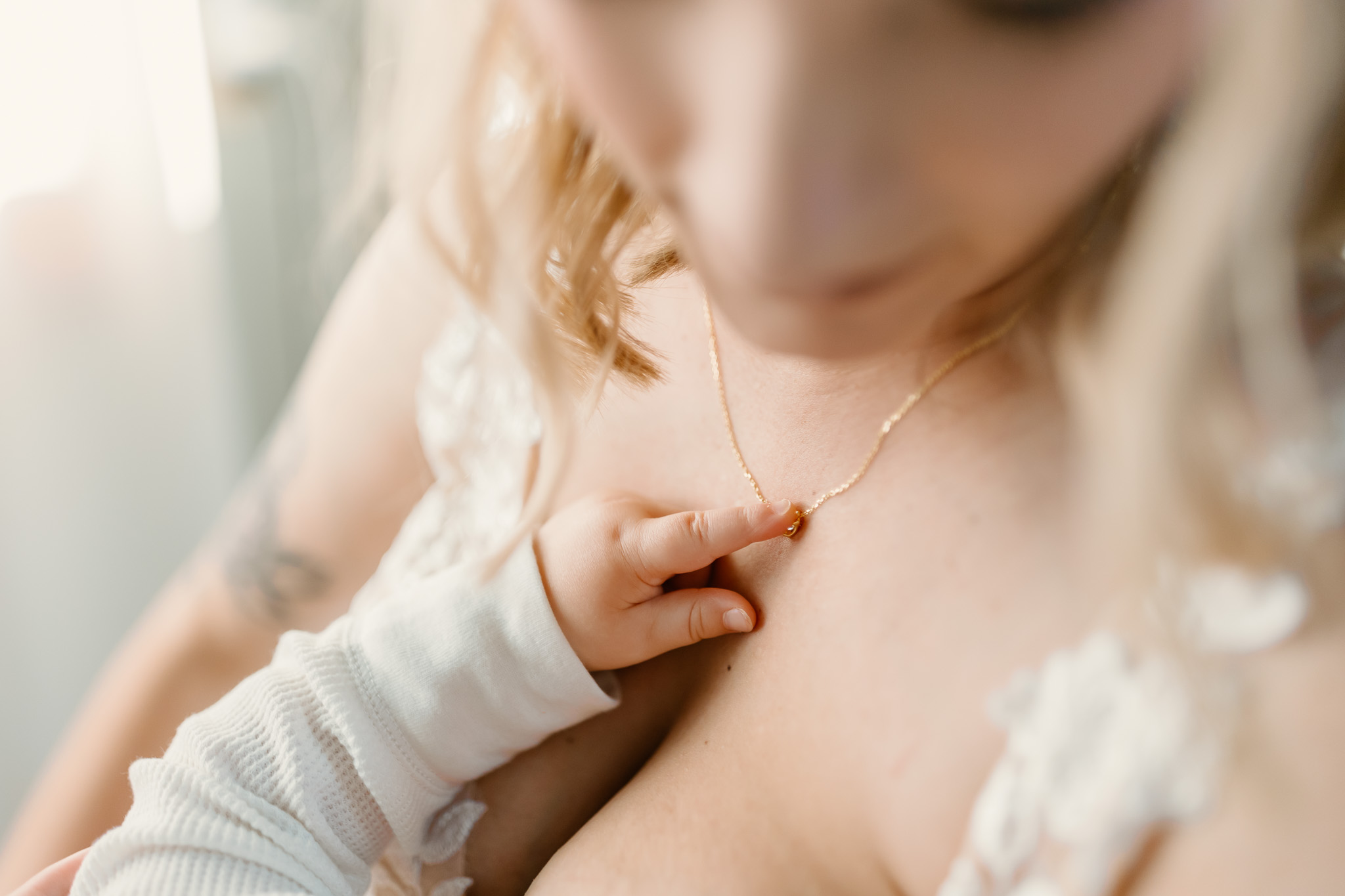 Bride holds her baby while baby admires her necklace before going down the isle