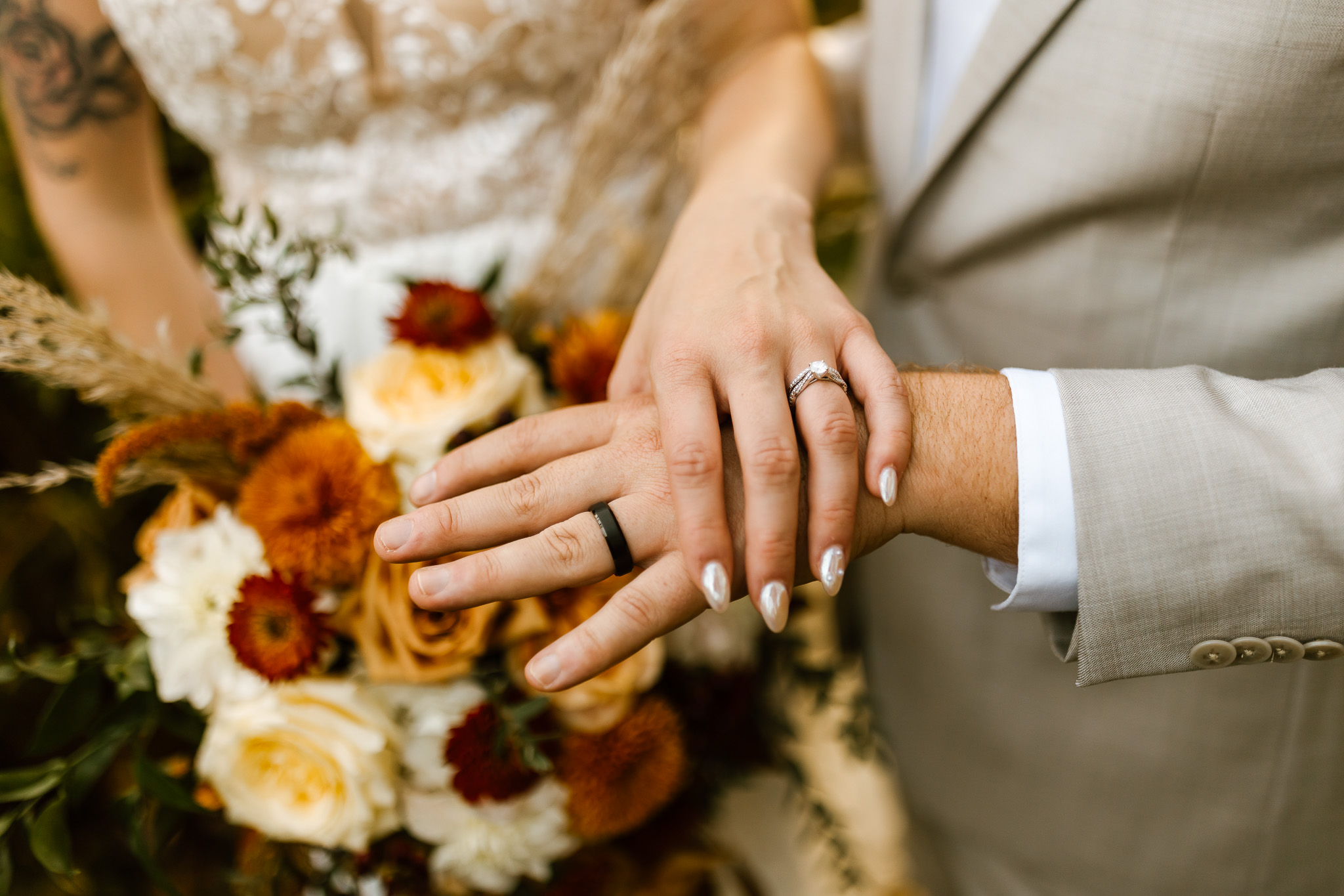 Bride and groom kiss outside a historic white New England home during their fall wedding, surrounded by autumn foliage and fallen leaves.