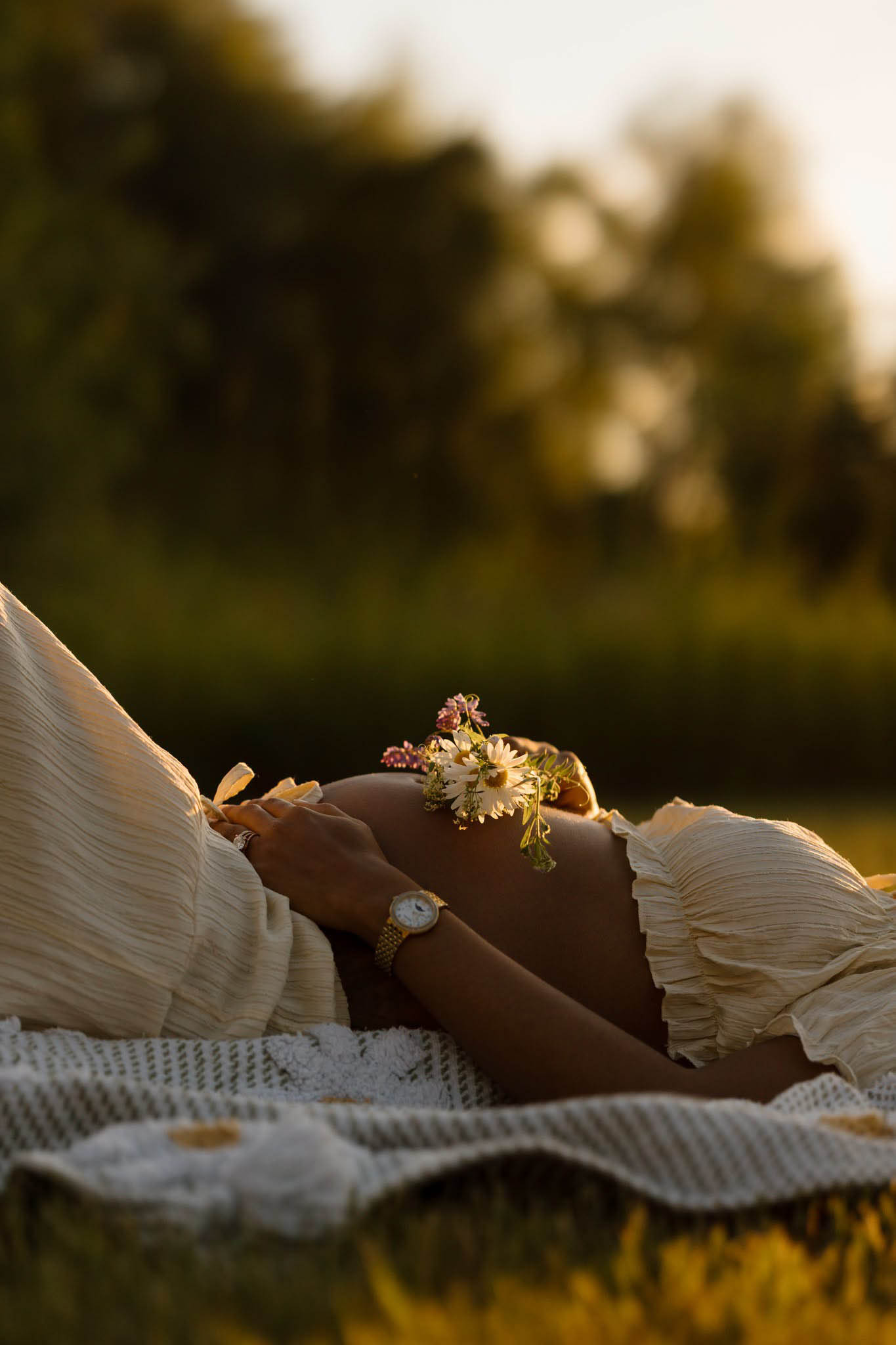 Maternity portrait of a belly where mom is laying down in the grass and holding flowers over her belly, sunset, golden hour, NH