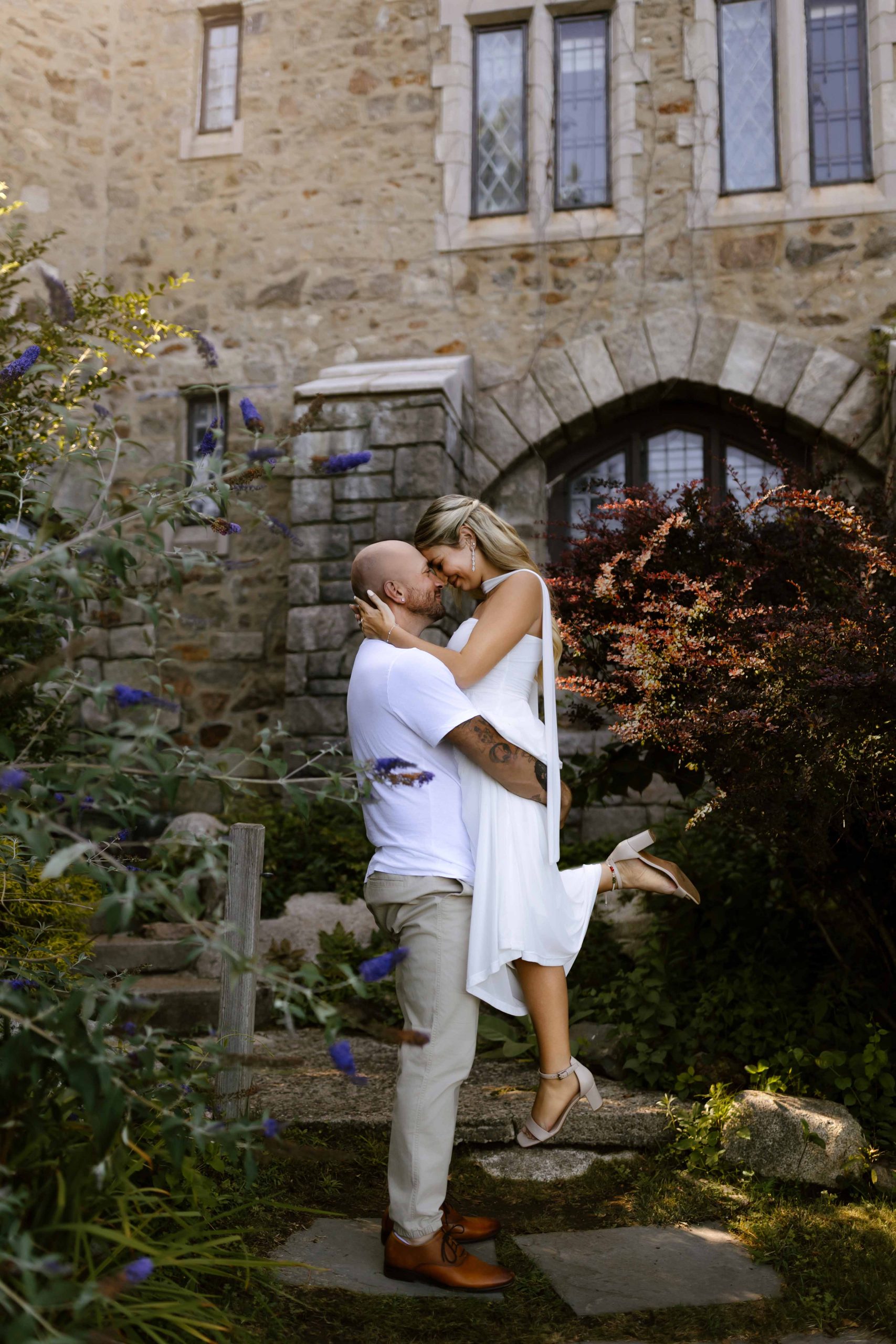 wedding portrait where husband is picking up bride and touching foreheads, hammond castle, ma