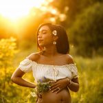 Maternity portrait where focus is on belly, mom's hand on her belly and holding flowers, nh