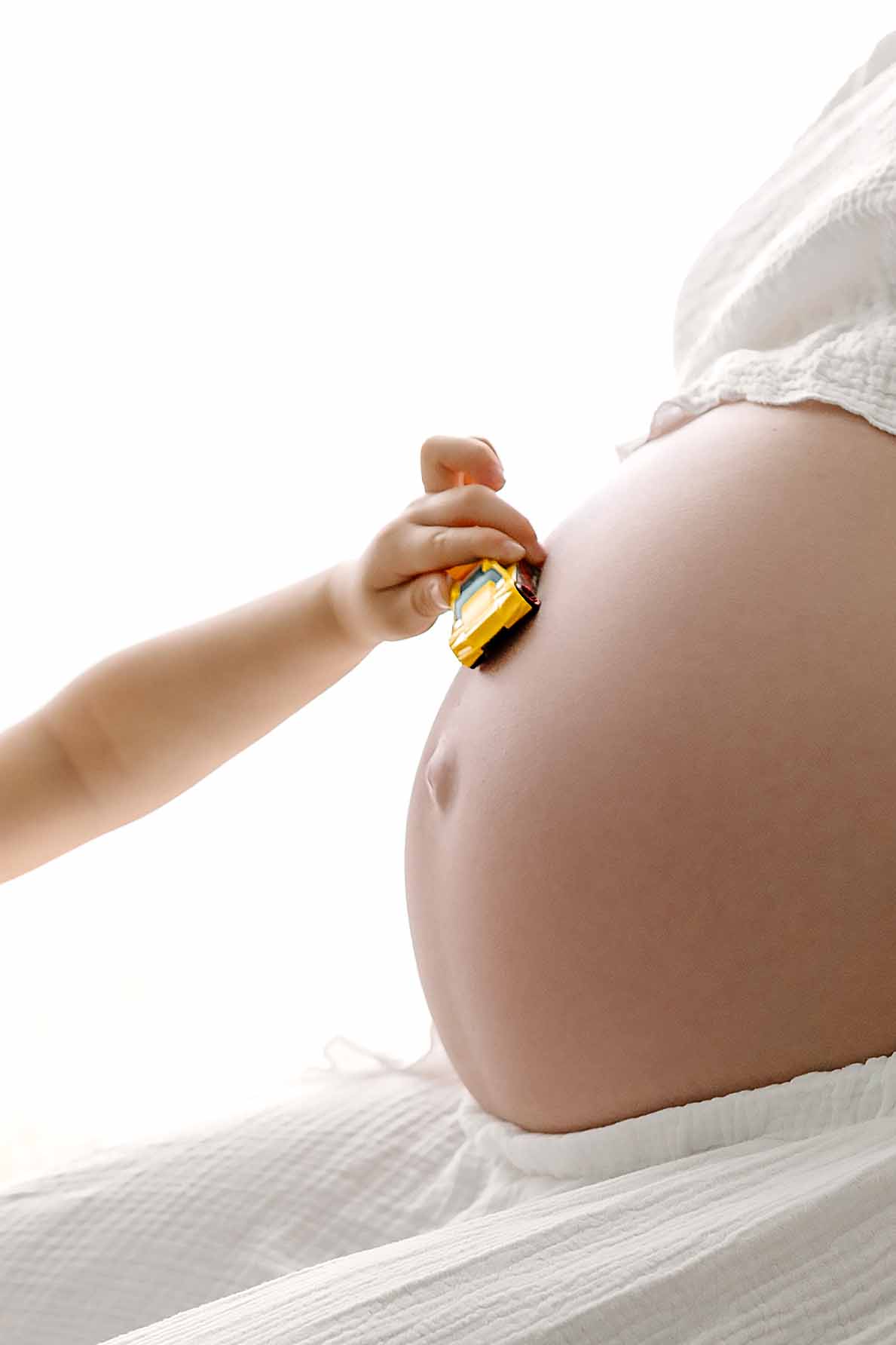 pregnant belly with child driving toy car over the bump NH