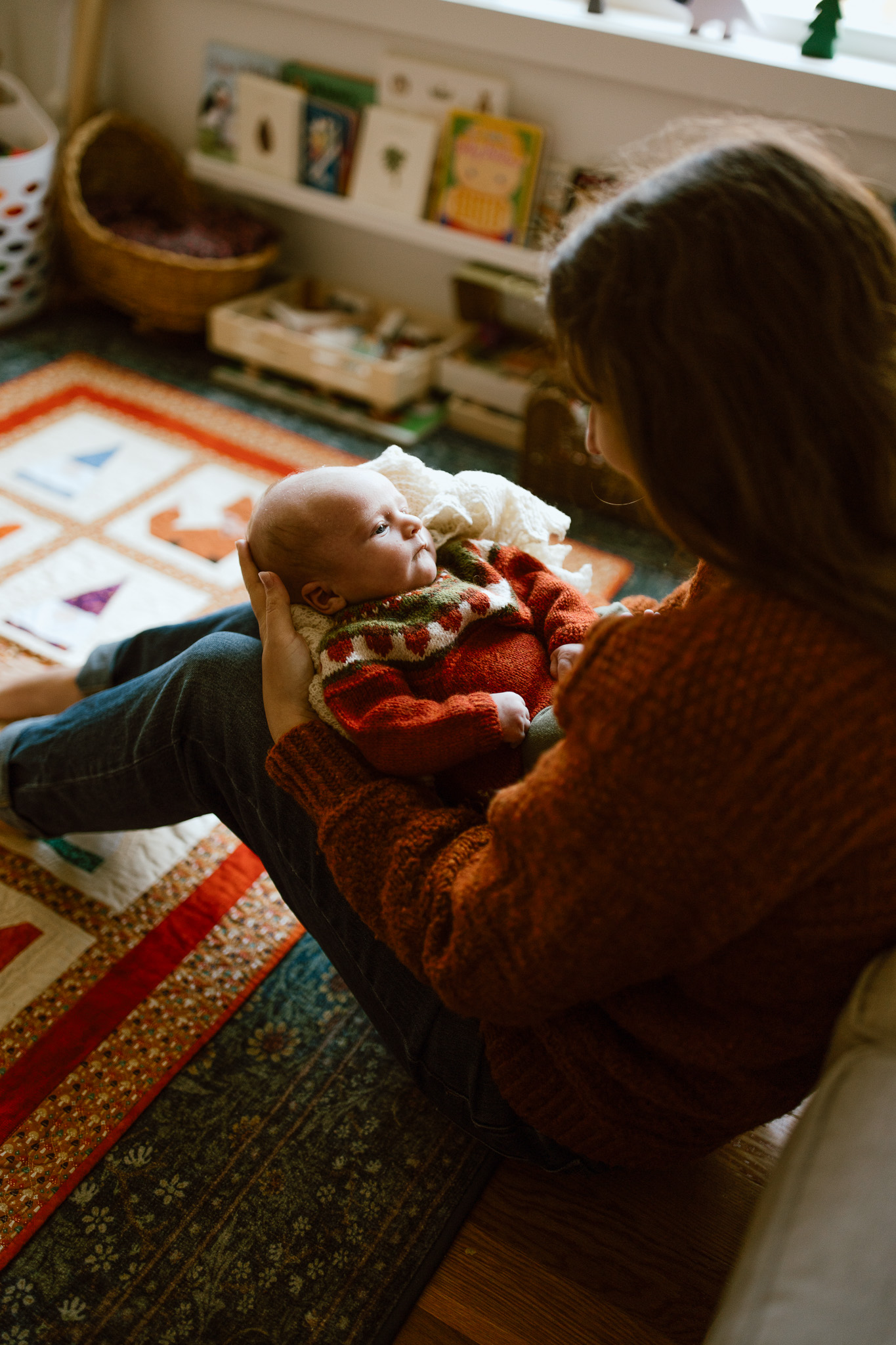 in-home newborn session where baby is sitting on mom's lap in living room