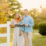 family holding sonogram with toddler at golden hour