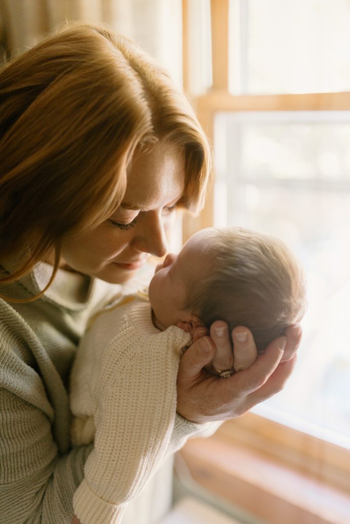 Lindsey and Mitchell cuddling their newborn daughter Claudia during an in-home newborn photography session in New Hampshire